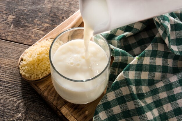 Verser le lait de riz en verre sur la table en bois.