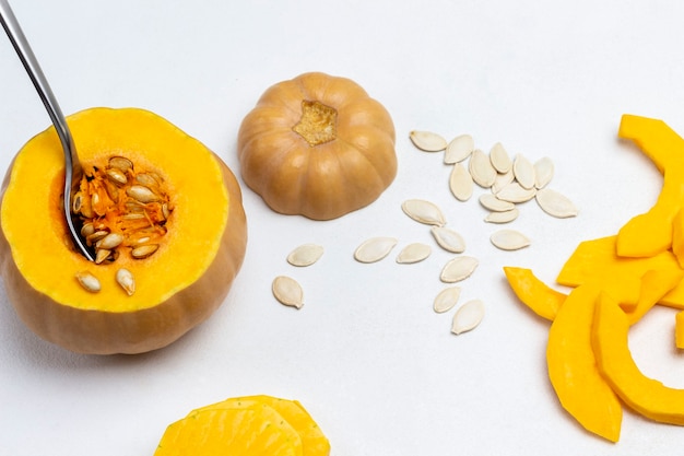 Verser la pulpe de citrouille sur une planche à découper. Citrouille en tranches et graines sur table. Fond blanc. Vue de dessus.