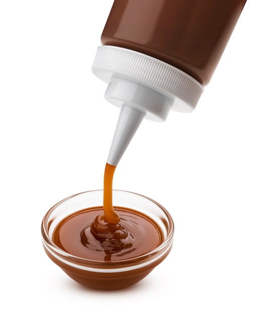 Verser la sauce caramel avec bouteille isolé sur blanc