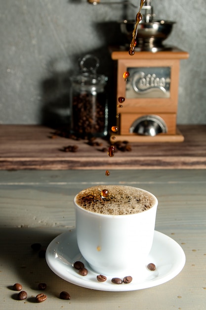 Verser une tasse de café créant des éclaboussures sur fond en bois.