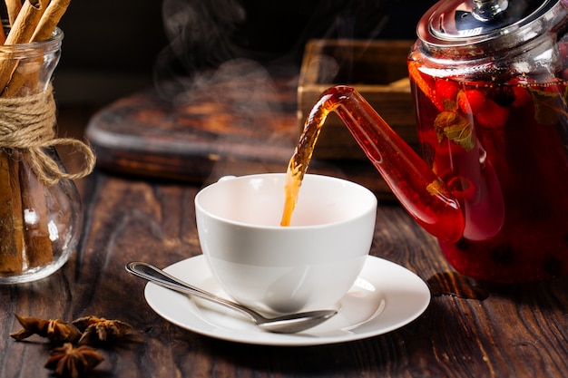 Verser le thé chaud aux baies dans une tasse de théière en verre