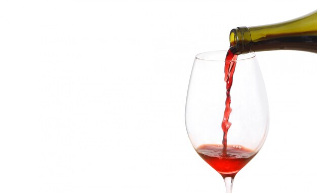 Verser le vin rouge dans le verre de bouteille sur fond blanc