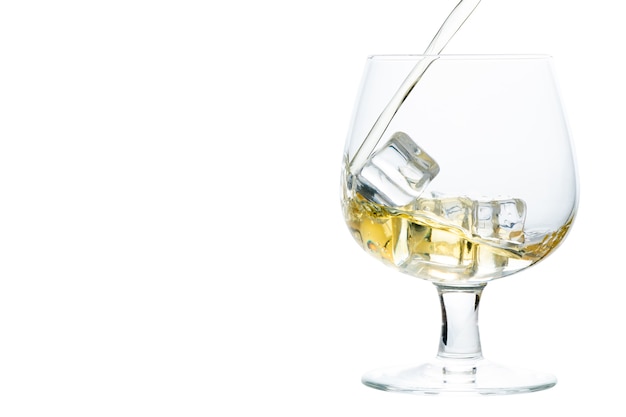 Versez du whisky ou du brandy sur un glaçon dans un verre Snifter ou Balloon isolé sur fond blanc, concept de boisson