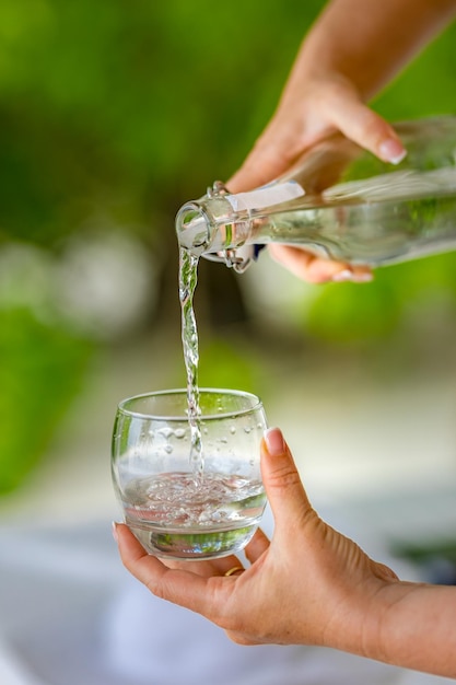 Versez l'eau d'une bouteille dans un verre. Versez un verre d'eau. Une image de verser un verre d'eau