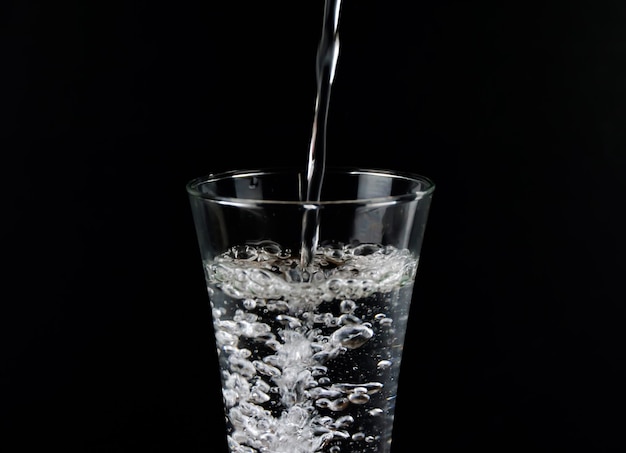 Versez de l'eau dans un verre séparé sur fond noir