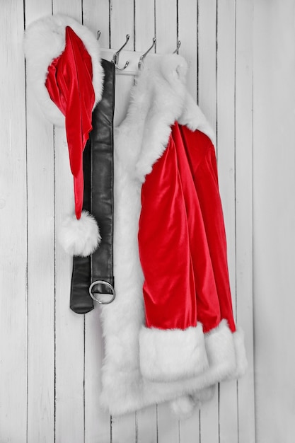 Photo veste de santa, chapeau et ceinture sur un mur blanc en bois