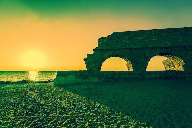 Vestiges de l'ancien aqueduc romain dans la ville antique de Césarée au coucher du soleil Israël