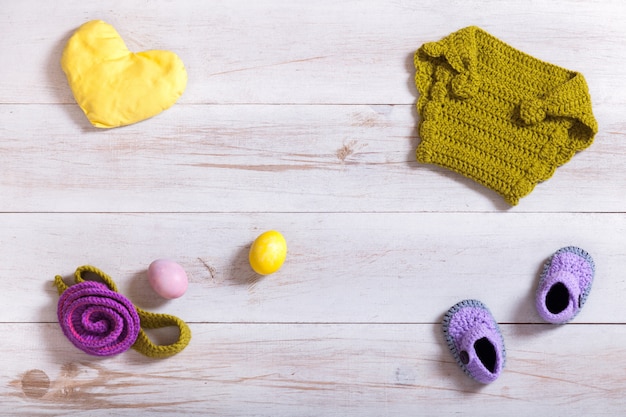 Vêtements et accessoires bébé tricoté sur fond de bois blanc