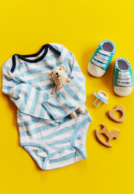 Vêtements et accessoires pour bébé sur fond jaune. Mise au point sélective.