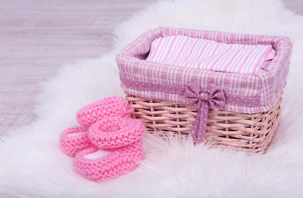 Photo des vêtements de bébé dans un panier sur le sol de la chambre.