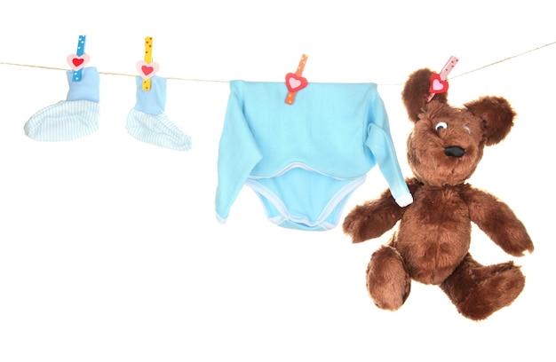 Vêtements bébé suspendu à une corde à linge isolé sur blanc
