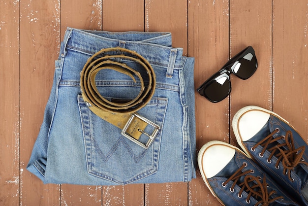 Vêtements chaussures et accessoires lunettes de soleil ceinture gumshoes chaussures et blue jeans sur fond de bois