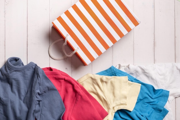 Vêtements colorés et sac à provisions sur fond de bois Concept de recyclage d'occasion