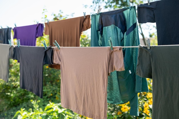 Vêtements de couleurs sombres et pastel accrochés à la corde lors d'une belle journée ensoleillée à l'extérieur des T-shirts masculins faisant la lessive dans la campagne