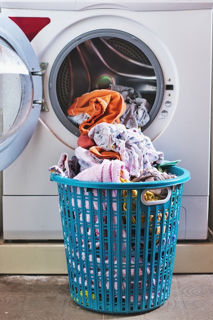 Photo vêtements dans le panier en face de la machine à laver.