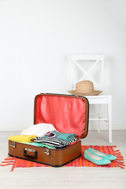 Vêtements féminins dans une vieille valise sur fond clair