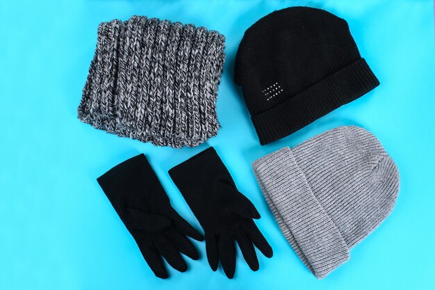 Vêtements d&#39;hiver, d&#39;automne, chapeaux, écharpes, gants sur fond bleu pastel.