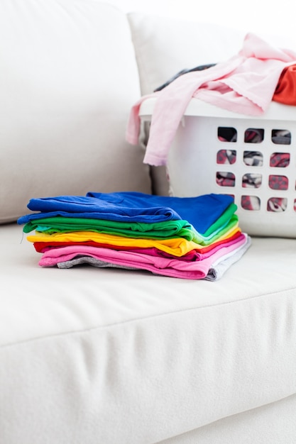 Vêtements lavés dans un panier et pile de linge propre sur le canapé