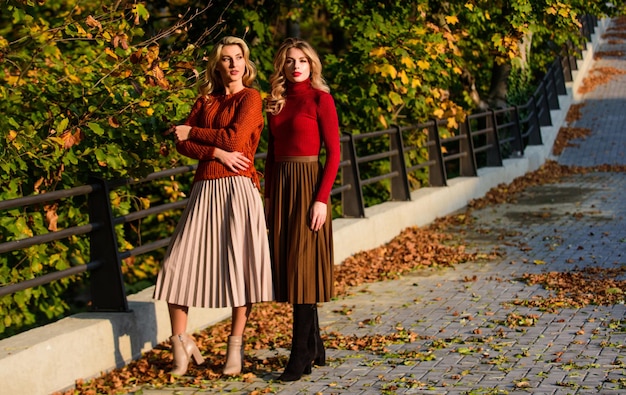 Vêtements à la mode Féminité et tendresse Amies filles Mode d'automne Jupe plissée tendance de la mode Femmes marchant dans le parc d'automne Tenue élégante d'automne Dames adorables profitant d'une journée d'automne ensoleillée