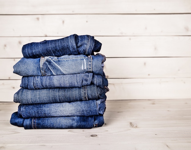 Vêtements à la mode. Tas de jeans sur un fond en bois