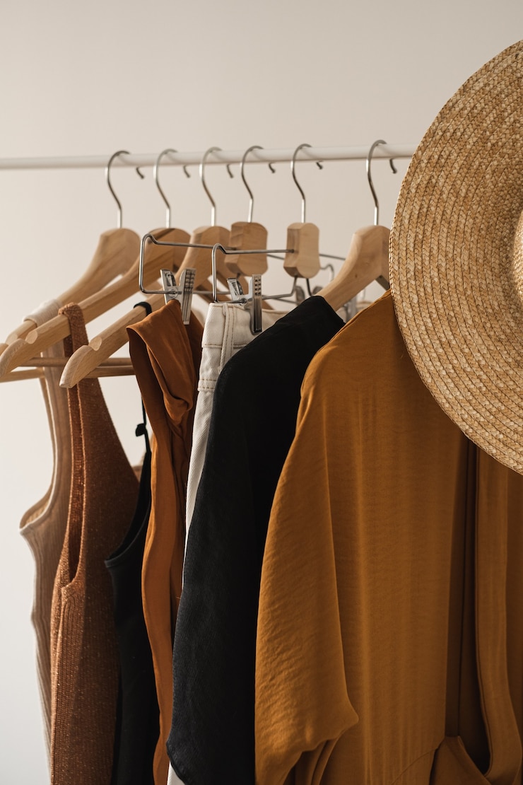 Photo vêtements pastel de mode minimal pour femmes. chemisiers féminins élégants, t-shirts, hauts, chapeau de paille sur un porte-vêtements sur blanc