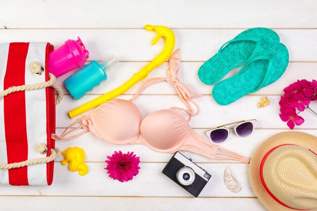 Vêtements de plage et accessoires sur un fond en bois blanc