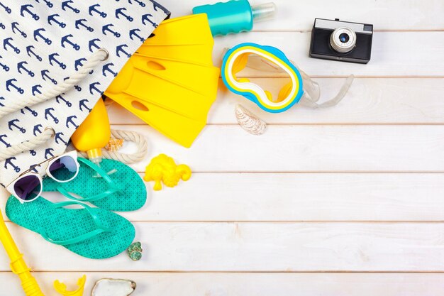 Vêtements de plage et accessoires sur un fond en bois blanc