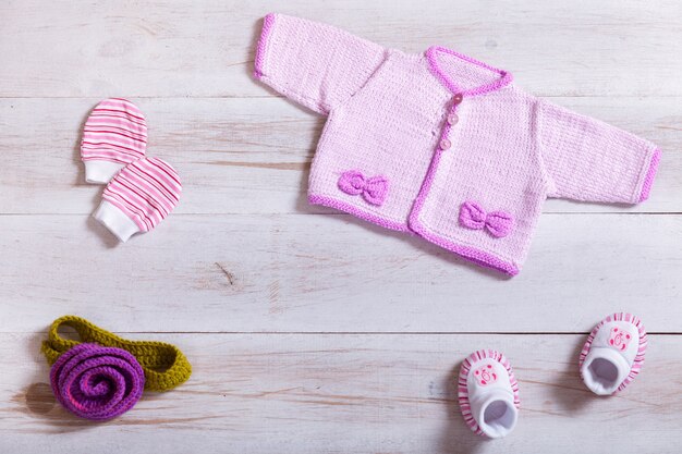 Vêtements pour bébés sur fond de bois blanc, pose à plat