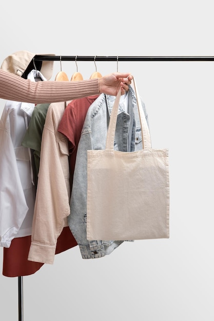 Vêtements pour femmes de base et sac écologique sur fond blanc Femme collection de vêtements sur un rack