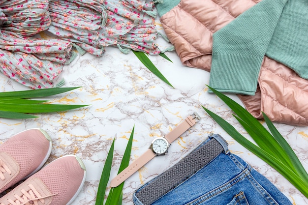 Vêtements pour femmes mode, feuilles tropicales, accessoires à la mode sur fond de marbre.