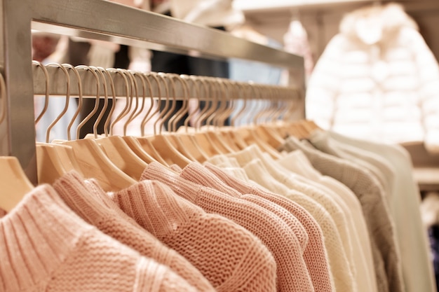 Vêtements pour femmes roses sur des cintres en bois sur rack dans un magasin de mode