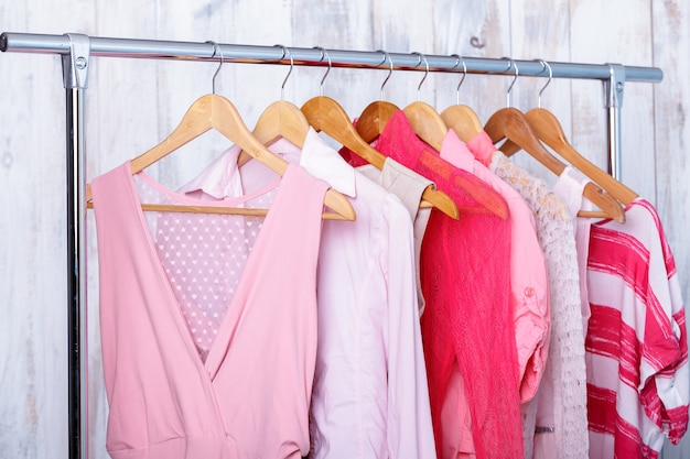 Vêtements pour femmes roses sur cintres en bois sur support dans un magasin de mode. placard femmes robes, chemisiers