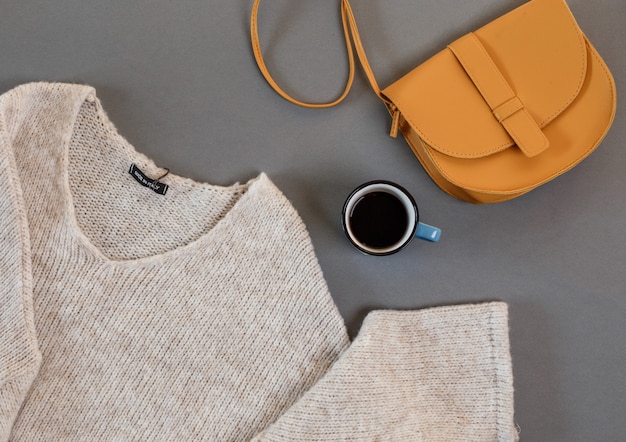 Des vêtements, une tasse de café, un sac pour femme disposé sur une vue de dessus de fond gris.