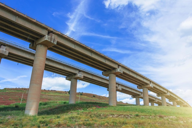 Le viaduc du pont de l'autoroute à deux virages prend en charge dans la vallée parmi les infrastructures de transport des collines verdoyantes