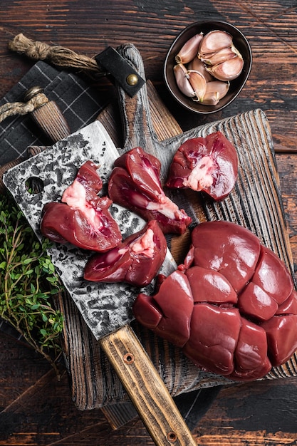 Viande d'abats frais de rein d'agneau cru sur planche de boucher avec des herbes Fond en bois Vue de dessus