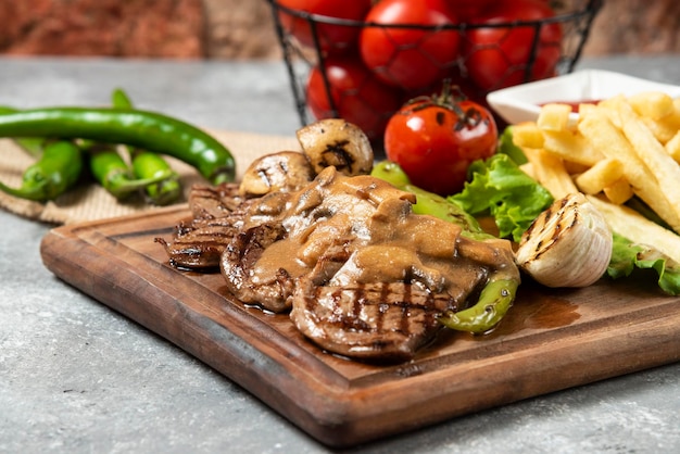 Viande d'agneau grillée avec frites sur plaque de bois