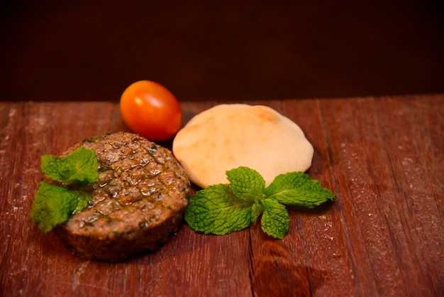 Viande arabe avec pain arabe, tomate et feuilles de menthe sur table