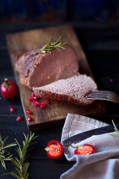 Viande au four au romarin et au poivron rouge. steak. du boeuf. dîner pour les hommes. photo sombre. Fond noir. planche de bois.