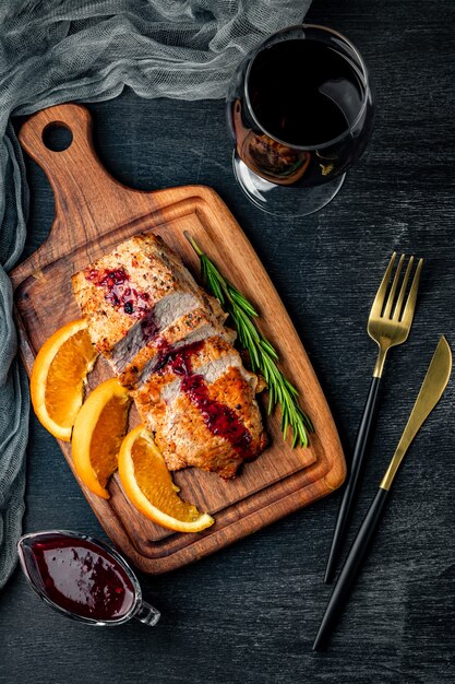 Viande au four avec sauce aux airelles et un verre de vin, vue du dessus.