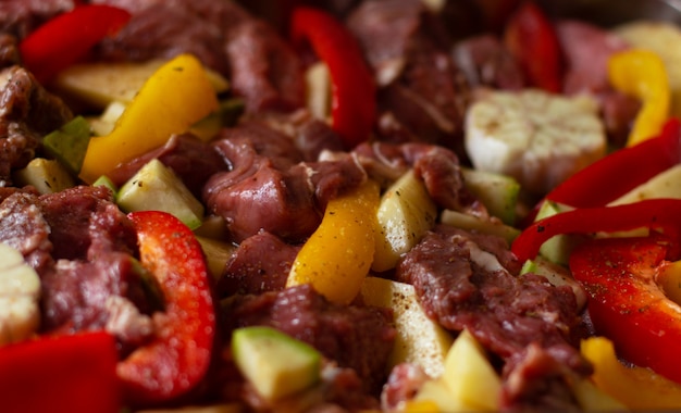 Photo viande de bœuf crue aux légumes crus: courgette, ail, poivron rouge et jaune aux épices naturelles et aux herbes