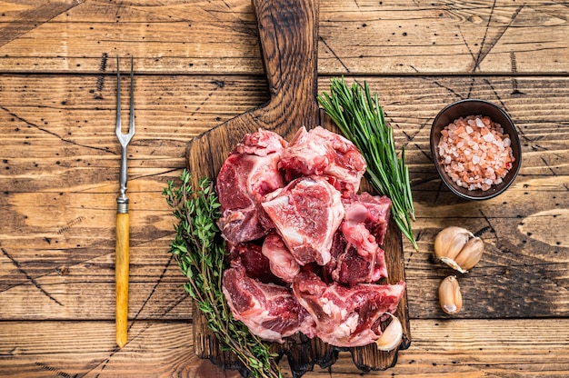 Viande de boeuf crue coupée en dés pour ragoût avec os. fond en bois. Vue de dessus.