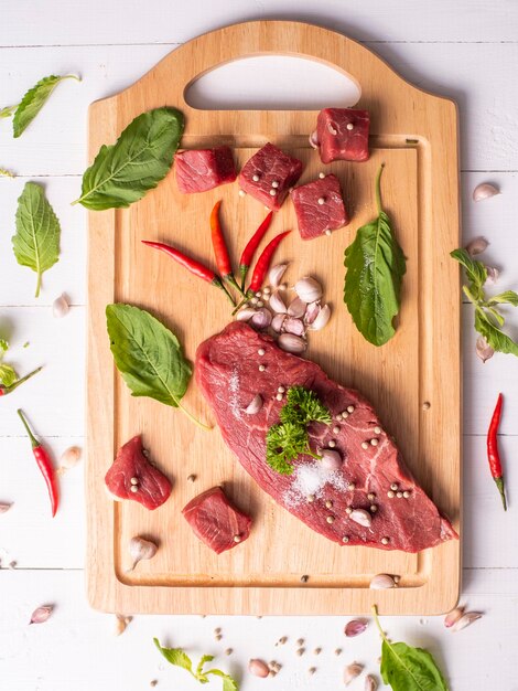 Viande de bœuf crue sur fond de bois blanc