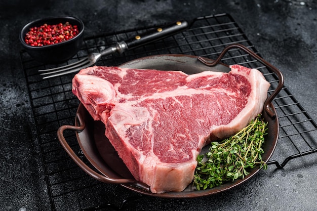 Viande de boeuf crue fraîche marbrée Tbone Steak sur un plateau en acier Fond noir Vue de dessus