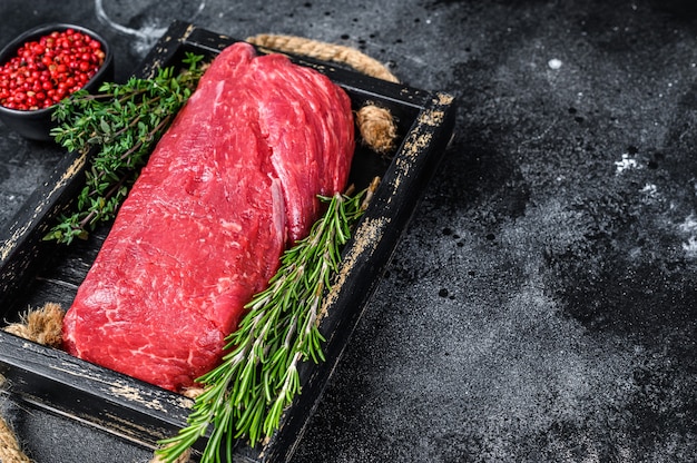 Viande de boeuf Filet entier cru sur un plateau en bois avec des herbes