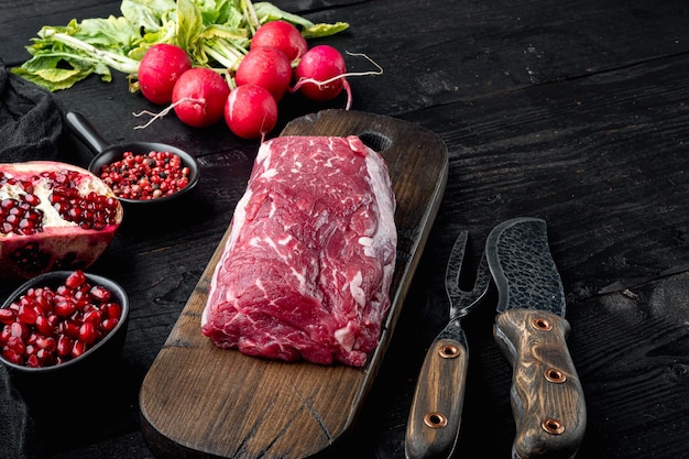 Viande de boeuf fraîche et crue Morceau entier de filet avec des steaks et des épices prêt à cuire sur fond de table en bois noir avec espace de copie pour le texte