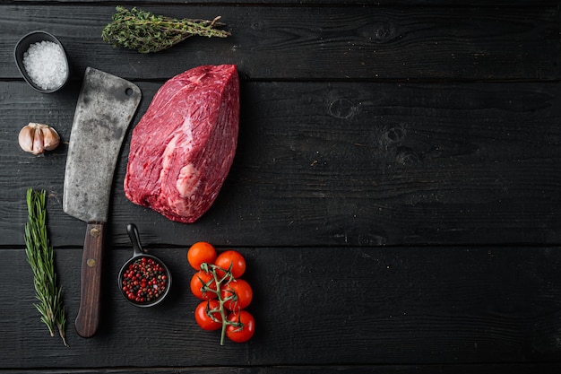 Viande de boeuf de poitrine de bœuf cru sertie de vieux couteau couperet de boucher, sur table en bois noir, vue de dessus à plat