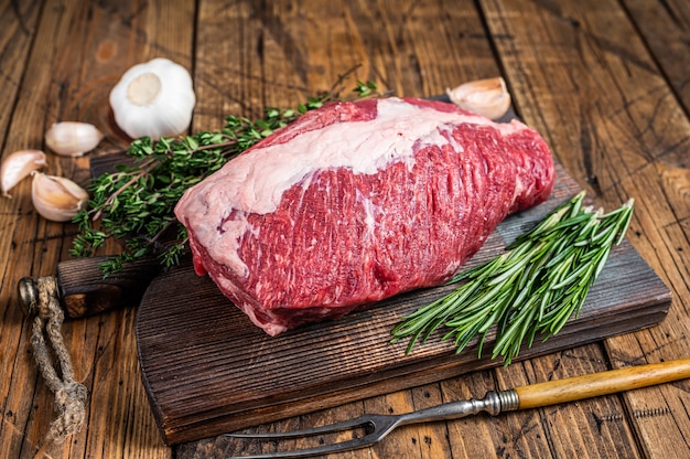 Viande de bœuf de poitrine crue fraîche coupée sur une planche de bois avec des herbes. en bois