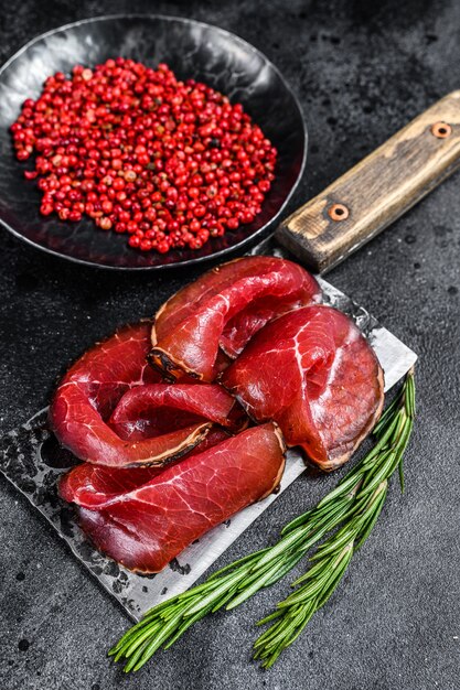 Viande de bœuf séchée Bresaola tranchée sur un couperet.