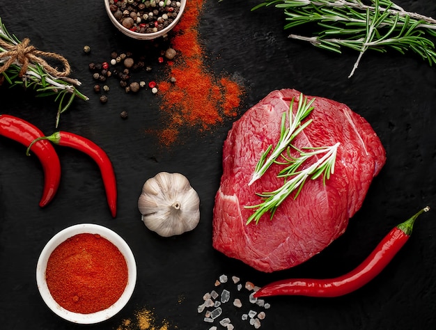 viande de boucherie emballée dans du papier. Un morceau de boeuf sur un béton noir avec différentes épices