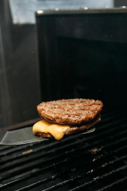 Viande de burger se préparant avec du fromage sur le gril fond noir